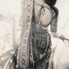 A black and white shot focusing on the stunning back and intricate details of this multi-colored lehenga, highlighting the craftsmanship of the blouse and skirt.