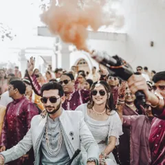 A fun and modern baraat entry! The couple makes their way through the cheering crowd on a scooter, complete with a colored smoke bomb for that extra bit of flair.