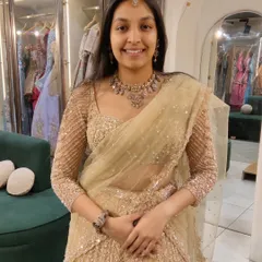 A happy client trying on a golden sequined lehenga. She paired it with a simple, elegant antique-finish necklace for a sophisticated wedding guest look.