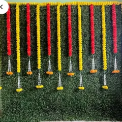 A greenery wall decorated with red and yellow marigold garlands. This classic color combination is perfect for traditional Indian ceremonies and celebrations.