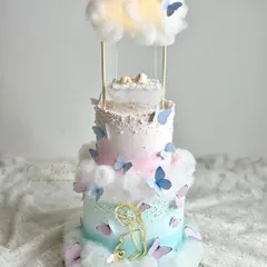 A dreamy, multi-tiered baby shower cake with a floating cloud and swing. This design combines structural techniques with soft textures like cotton candy clouds.