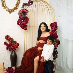 A beautiful portrait of a mother and her son, eagerly awaiting the new arrival. The deep red gown and floral theme create a rich, warm, and loving atmosphere.