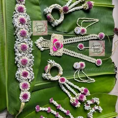 A full floral jewellery set in white and purple. This shows a kamarband, necklace, hath phool, and other pieces that can be created for various festive occasions.