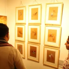 Visitors admiring my series of object studies on brown paper during the exhibition. It is always rewarding to see people engage with the details of each piece.