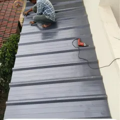 Our installer works on top of a puff sheet roof, securing the panels. This image captures the hands-on effort and attention to detail required for a professional, leak-proof installation.
