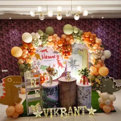 A friendly dinosaur-themed first birthday with a custom backdrop and an earthy-toned balloon arch.