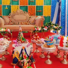 A complete platter decoration for a half-saree ceremony. The setup includes dolls, decorated fruit baskets, and sweet trays, all arranged to create a festive and colorful display.