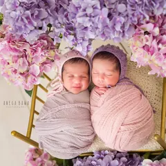 Sweet dreams, little ones. Dressed in coordinating bonnets, these twin girls are sleeping peacefully side-by-side. Capturing twins requires special care and patience to get these perfect moments.