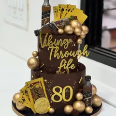 Turning 80 and still vibing through life. This classy two-tier chocolate cake celebrates a timeless spirit with a dash of whisky, golden playing cards, and good vibes only.