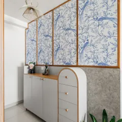 A well-thought-out foyer can make a living room feel more expansive. Here, we used light-toned furniture, curved details, and a beautiful blue and white wallpaper to create a light and airy entrance.