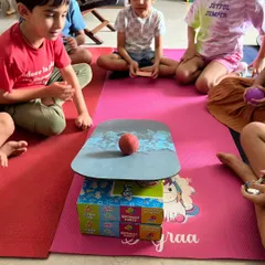A group of kids intently watching an experiment about balance and center of gravity. Every moment is a learning opportunity.
