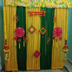I offer traditional decoration services for pre-wedding functions like the Haldi ceremony. This backdrop uses vibrant yellow and green drapes, marigold flower garlands, and traditional Indian hangings to create an authentic and festive atmosphere for your event.