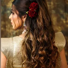 A beautiful and modern hairstyle featuring soft, romantic waves accessorized with two deep red roses. This look is perfect for an engagement or reception party.