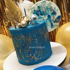 An asymmetrical cake I made for my brother's birthday. This modern design features a bold blue ganache with a gold stenciled pattern, topped with a disco ball, feathers, and an abstract chocolate sail.