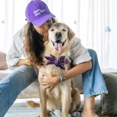 "Dog Mom" and proud! A woman wearing a "Dog Mom" cap shares a loving hug with her Golden Retriever during a special Mother's Day studio session.