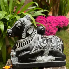 Here is a majestic seated Nandi, Lord Shiva's sacred mount, symbolizing strength and devotion. This piece is carved from a single block of stone with extensive detailing on the adornments, making it a powerful guardian for a temple-inspired entrance.
