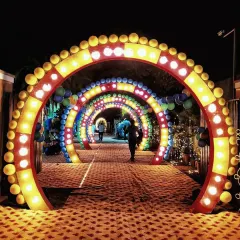 A fun and vibrant entrance for a party or mela-themed event. This setup features a series of colorful, illuminated arches that create a tunnel effect for guests to walk through.