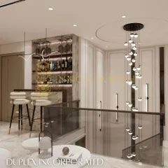 For this duplex, I incorporated a luxurious home bar counter. The design features backlit shelving for bottles, stylish bar stools, and a stunning cascading chandelier over the staircase, creating a perfect spot for entertaining.