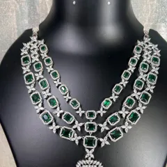 A still image of the stunning three-tiered emerald green and American diamond necklace. This rental piece features a large pendant and intricate detailing, perfect for a high-fashion statement.