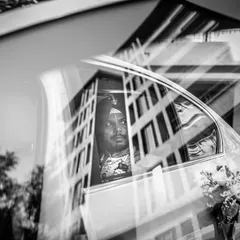 An artistic, reflective shot of the groom in his car. The black and white photo captures a moment of thought and anticipation on his way to the venue.