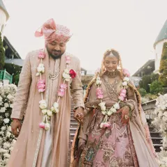 Walking down the steps together, their outfits blend seamlessly with the romantic, flower-filled setting. This is what perfectly coordinated couple styling looks like.