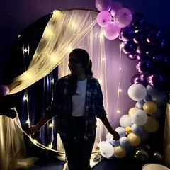 A guest enjoying the decorated space during a friends' get-together. The ambient lighting and balloon arch make even a casual hangout feel special.