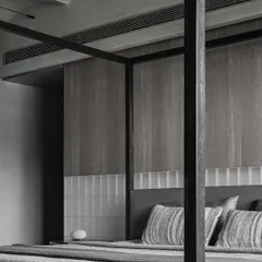 The headboard wall in the Vaulted Haus master bedroom features a combination of frosted glass bricks and grey veneer. The glass bricks can be backlit, transforming the wall into a source of soft, ambient light for the entire room.