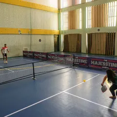 A player lunges for a low shot on our one-of-a-kind synthetic pickleball court, designed for speed and precision.