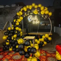 A close-up of the 'Bride to be' photo backdrop. This one features a black and gold balloon ring with a neon sign, perfect for taking pictures.
