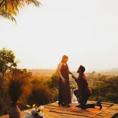 A classic proposal during the golden hour. He gets down on one knee on a scenic wooden deck overlooking a valley, creating the perfect romantic setting to ask the big question.
