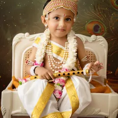 A handsome little boy dressed as Lord Krishna for Janmashtami. The detailed costume, complete with a crown and flute, is provided by my studio.
