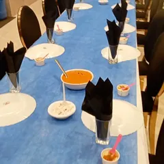 A long view of our formal dining setup. The striking blue and black theme, with neatly folded napkins and pre-set dishes, shows our ability to execute a sophisticated and large-scale seated dinner service.