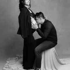 A tender and modern black and white portrait. The father-to-be gently kisses the baby bump, creating a timeless and intimate memory of this special time.