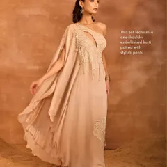 The Talia Kurti Set in a soft beige. This modern piece features a one-shoulder embellished kurti with a striking cutout and an elegant drape, paired with stylish pants.
