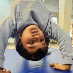 A different perspective. This young gymnast is practicing a bridge, building back flexibility and arm strength. This upside-down view shows his confidence and progress.