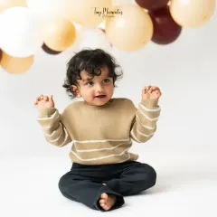 A perfect little sit. This milestone photo showcases his newfound sitting skills against a clean, minimalist backdrop with neutral-toned balloons.