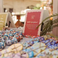 A 'Grab & Go Galore' station at a Parisian-themed Mehendi, featuring hand-painted ceramic knobs and cookies as unique, artistic favors for guests to take home.