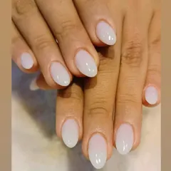 A beautiful "milky white" manicure on oval-shaped nails, offering a soft, clean, and modern alternative to a stark white.