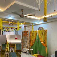 A combined look at the home decoration, showing the decorated pooja mandap and the floral hangings from the ceiling that tie the whole space together.