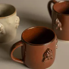 A collection of student-made mugs, each with its own unique personality. This one features beautiful sprig work inspired by South Indian temple architecture.