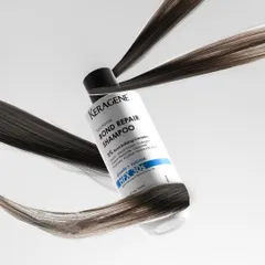 A conceptual shot showing strands of hair wrapping around a bottle of bond repair shampoo, visually communicating the product's function in a creative way.