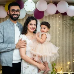 A lovely family portrait taken during a first birthday photoshoot, with the parents and their daughter posing together.