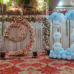 The main stage for the naming ceremony, featuring a large floral arch and a circular floral swing for the baby. We also included a custom balloon display with the names of family members.