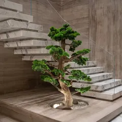 This wide shot shows the faux bonsai's placement in relation to the floating staircase, creating a harmonious balance between natural form and contemporary architecture.