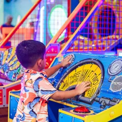 A young gamer completely focused on a classic arcade machine. These games are great for developing hand-eye coordination.