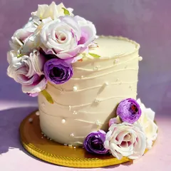 A tall, elegant cake with a beautiful arrangement of purple and white sugar flowers. The subtle texture and pearl details on the buttercream add a touch of sophistication.