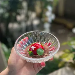 A luxurious Goose Liver Bonbon, coated in a cherry gel and served on a bed of cacao crumbs. A perfect balance of rich, sweet, and earthy flavors.