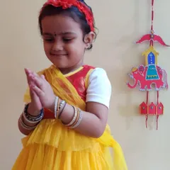A young girl dressed for Dusshera celebrations stands beside her beautiful, handcrafted wall hanging. Art is integrated with our cultural celebrations, making learning about traditions a creative, hands-on process.
