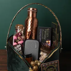 A truly grand gesture, this green velvet basket is filled with premium items. It includes a personalized copper bottle, a portable speaker, a jar of black oudh and rose, and a variety of gourmet chocolates and snacks, designed to make a significant impression.