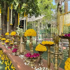 A close-up of a traditional Haldi decor setup, featuring brass vessels filled with vibrant marigolds and rose petals.